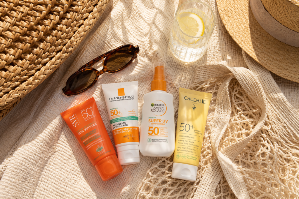 Crème solaire : SPF, texture et type de peau pour bien choisir 3 Sélection de crèmes solaires SPF 50 dans une ambiance cosy estivale avec accessoires de plage et décoration naturelle.